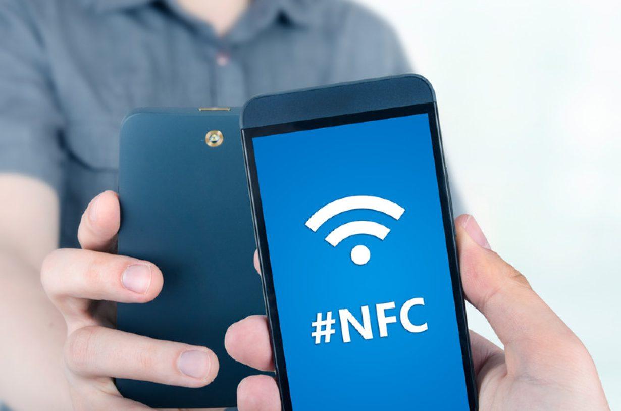 Hand holding smartphone with NFC technology NFC/RFID and NTAG®TagTamper